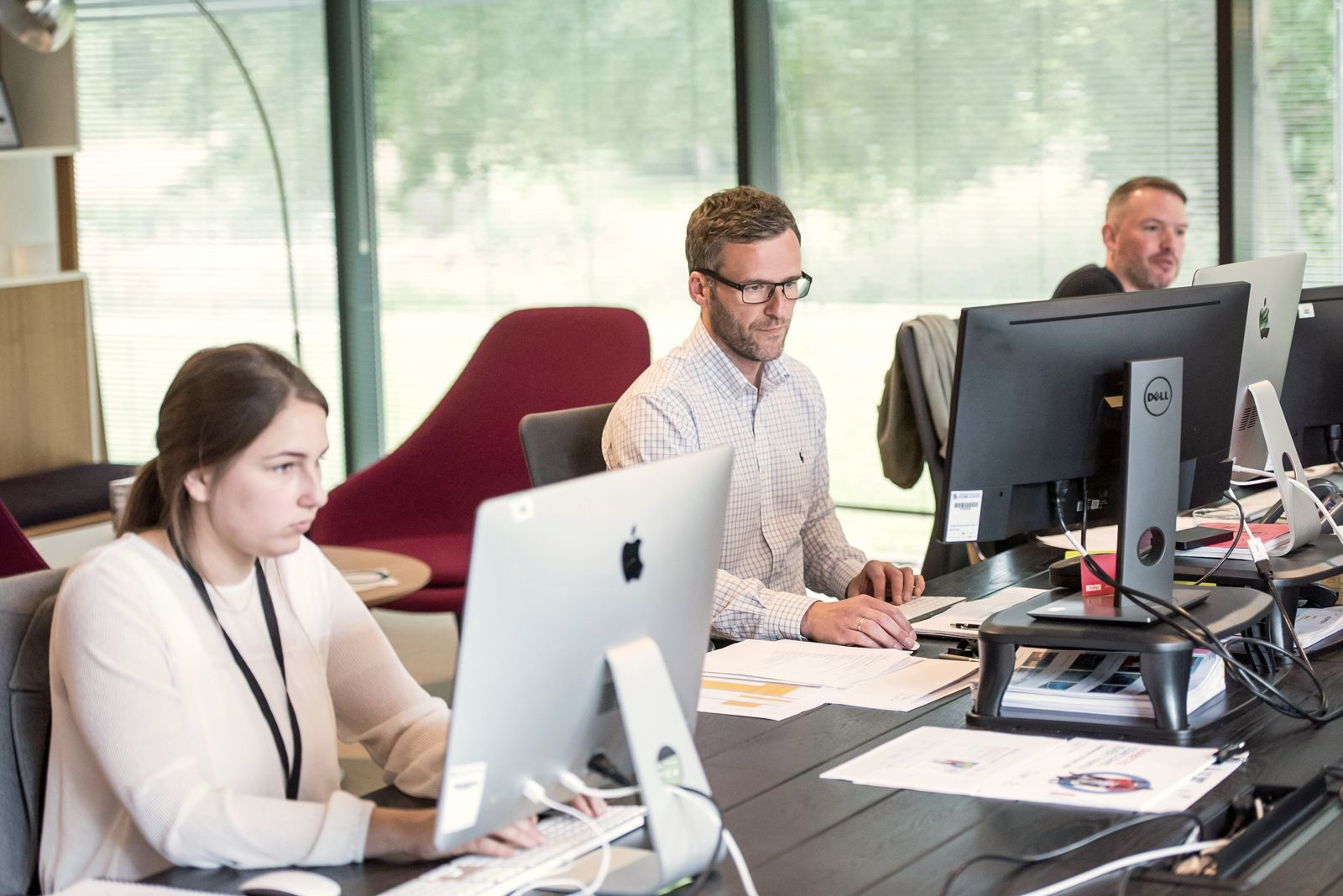 Konzentrierte Arbeit an Bildschirmen und Unterlagen im Büro